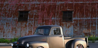 01 A matte two tone 1954 Chevy pickup with chrome wheels posed against a rustic barn backdrop