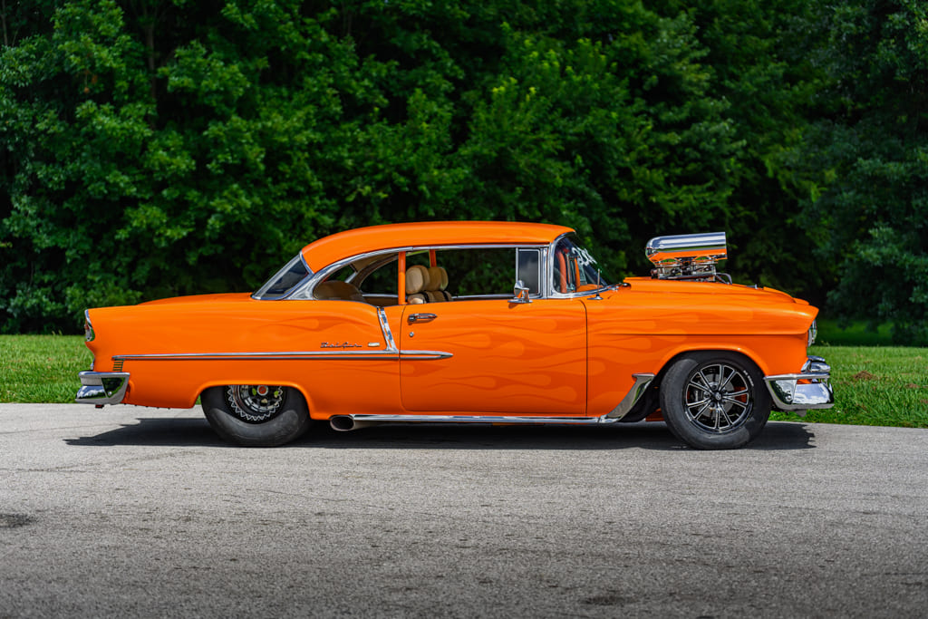 007 Rear three quarter view of an orange 1955 Chevy Bel Air parked on a driveway