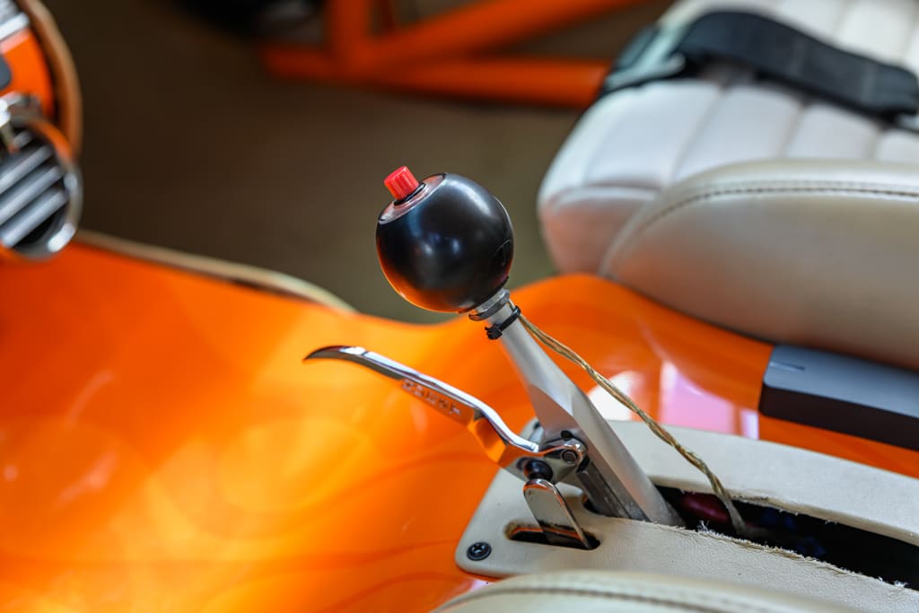 017 Gear shifter with a black knob in a custom orange interior of a 1955 Chevy Bel Air