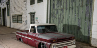 01 1965 Chevy C10 lowered stance red patina finish parked beside an industrial building