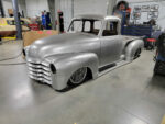 001 A raw metal '51 Chevy truck body undergoing custom restoration in a workshop