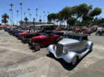 01 A lineup of classic 1930s Ford roadsters on display under palm trees at a car show