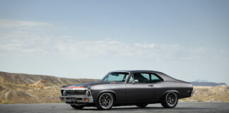 001 A side profile of a 1971 Chevrolet Nova with dark gray paint aftermarket wheels and a lowered stance on an open road