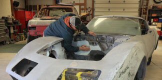 01 A 1971 Corvette undergoing bodywork restoration with a person sanding the engine bay