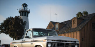 12 Front view of a 1974 Ford F 100 parked near a lighthouse featuring modern wheels and a clean chrome grille