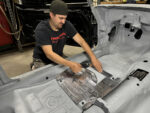000 Technician applying sound deadening insulation in the interior of a Camaro's floorpan