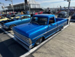 10 Bright blue Ford pickup with chrome trim and lowered stance parked among other classics at the show