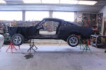 01 1965 Ford Mustang Fastback body undergoing restoration mounted on jack stands with wheels removed for chassis work