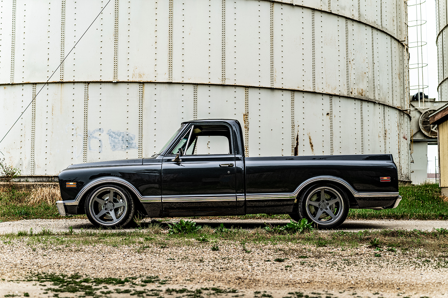 04 1969 Chevy C10 side profile featuring five spoke custom wheels and sleek black finish