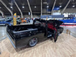 05 Black custom C10 with red interior and unique wheels on a wood display platform