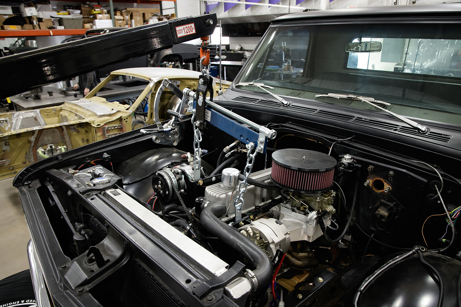 05 Engine crane lifting small block engine into the Chevy C10 s engine bay during custom build