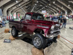12 Burgundy 1959 Chevrolet Apache with off road tires and chrome accents elevated on rocks for display