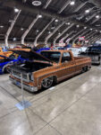 17 Bronze Chevrolet C10 square body pickup with chrome wheels and hood open in exhibit hall