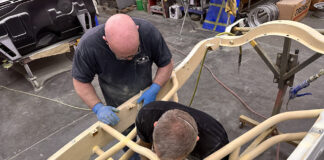 01 Fabrication specialists sanding and preparing a roadster chassis for finishing touches in a restoration shop