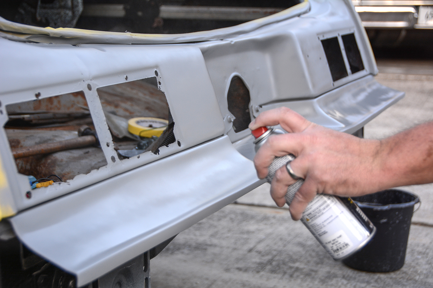 021 A hand sprays primer onto a prepared surface smoothing over a repaired and sanded area of a vehicle panel