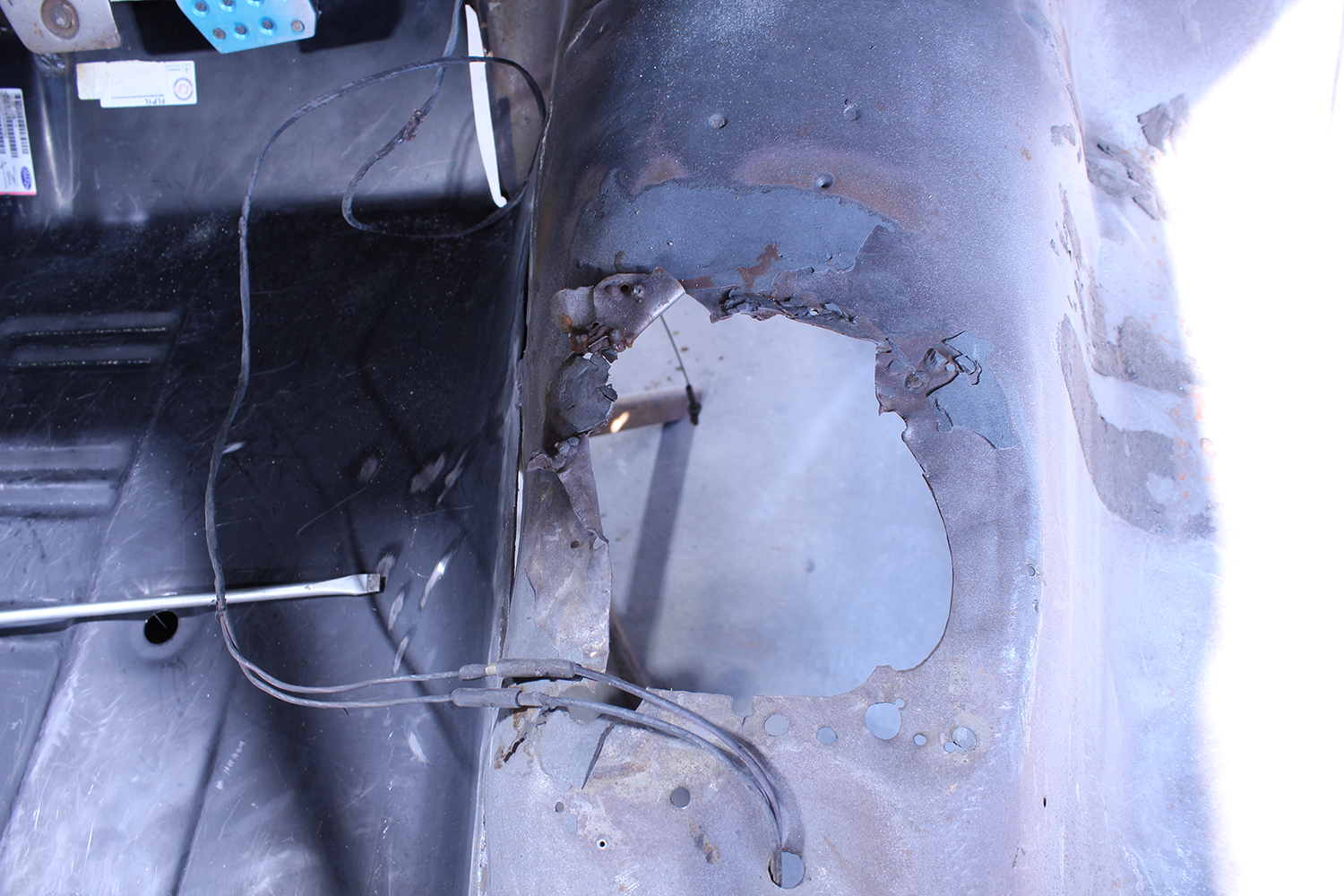 03 Severe rust damage on 1965 Ford Mustang floor pan with exposed wiring and corroded edges