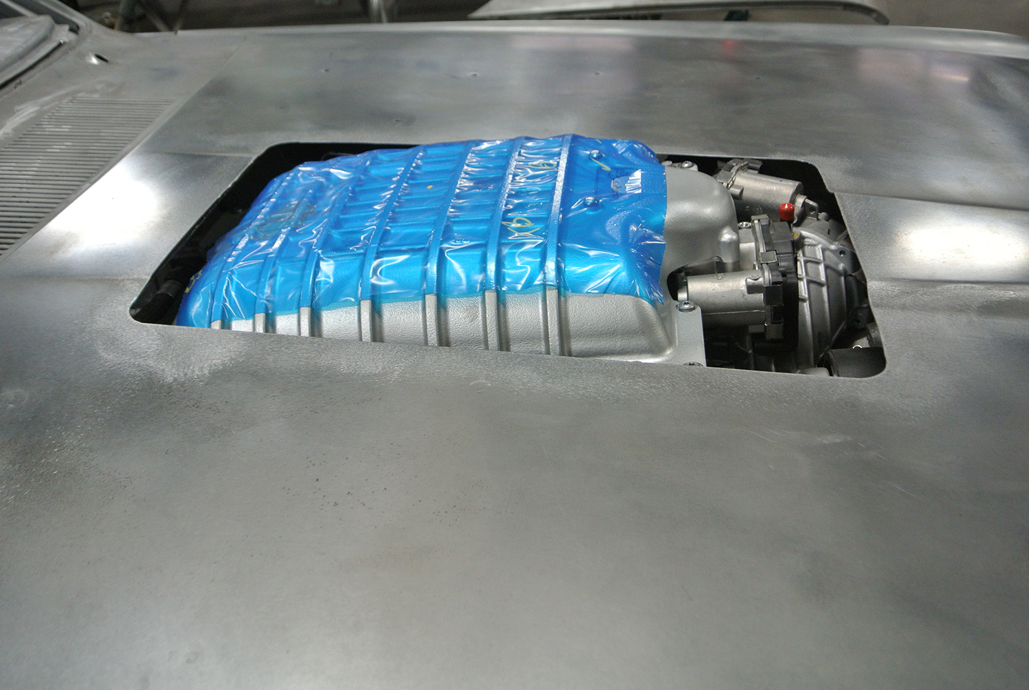 06 Custom hood showing supercharger intake wrapped in protective blue film during fitting