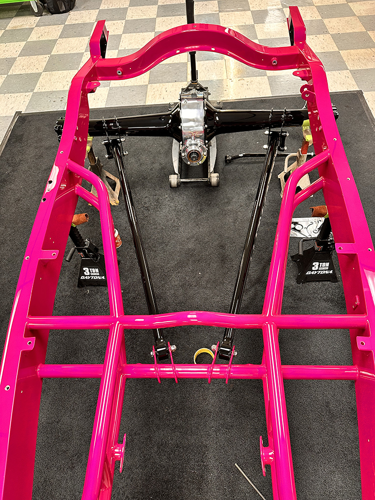 07 Glossy hot pink roadster frame with rear suspension components being reassembled for final assembly