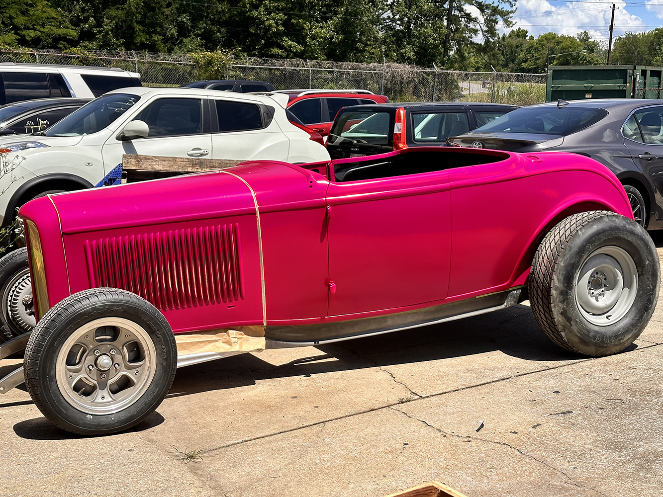 13 Fully assembled 1932 Ford roadster with a vibrant pink finish parked outside the workshop