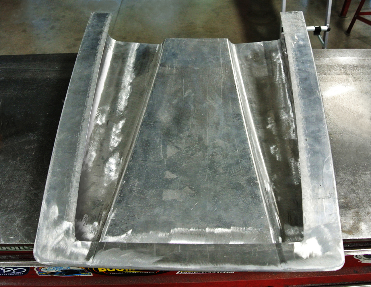 13 Partially constructed hood panel showcasing raw metal and shaping work with visible contour lines