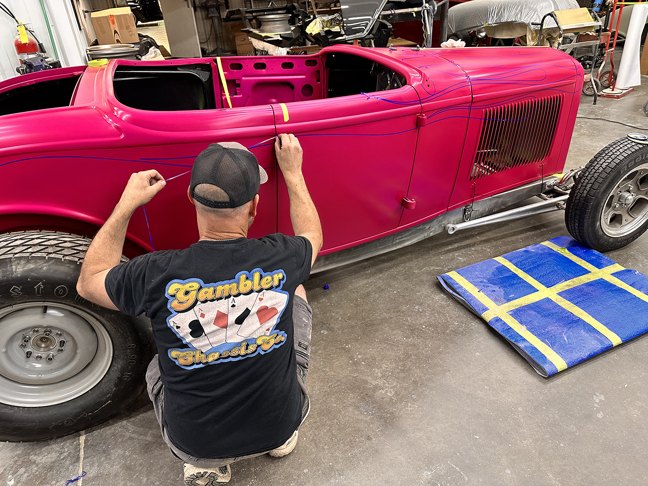 14 Custom flames being outlined on a hot pink 1932 Ford roadster by a skilled technician