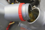 000 Close up of motor oil being poured into an engine filler opening silver and red cap visible