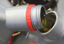 000 Close up of motor oil being poured into an engine filler opening silver and red cap visible