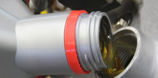 000 Close up of motor oil being poured into an engine filler opening silver and red cap visible