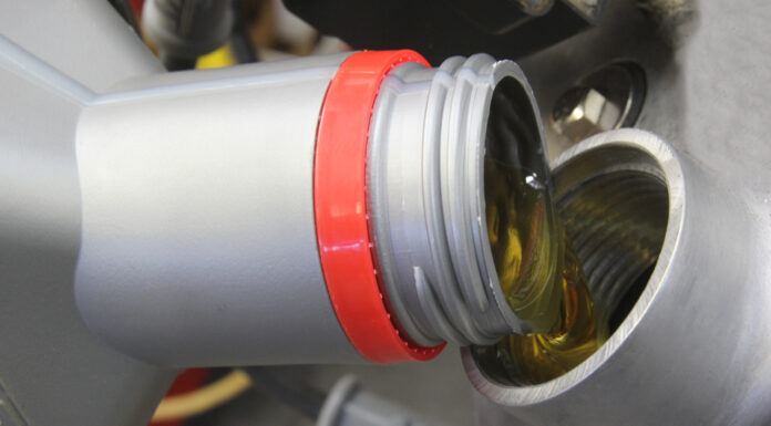 000 Close up of motor oil being poured into an engine filler opening silver and red cap visible