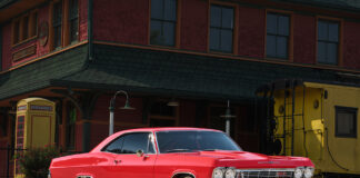 001 1965 Chevrolet Impala Super Sport red parked near a vintage train station custom wheels restored exterior