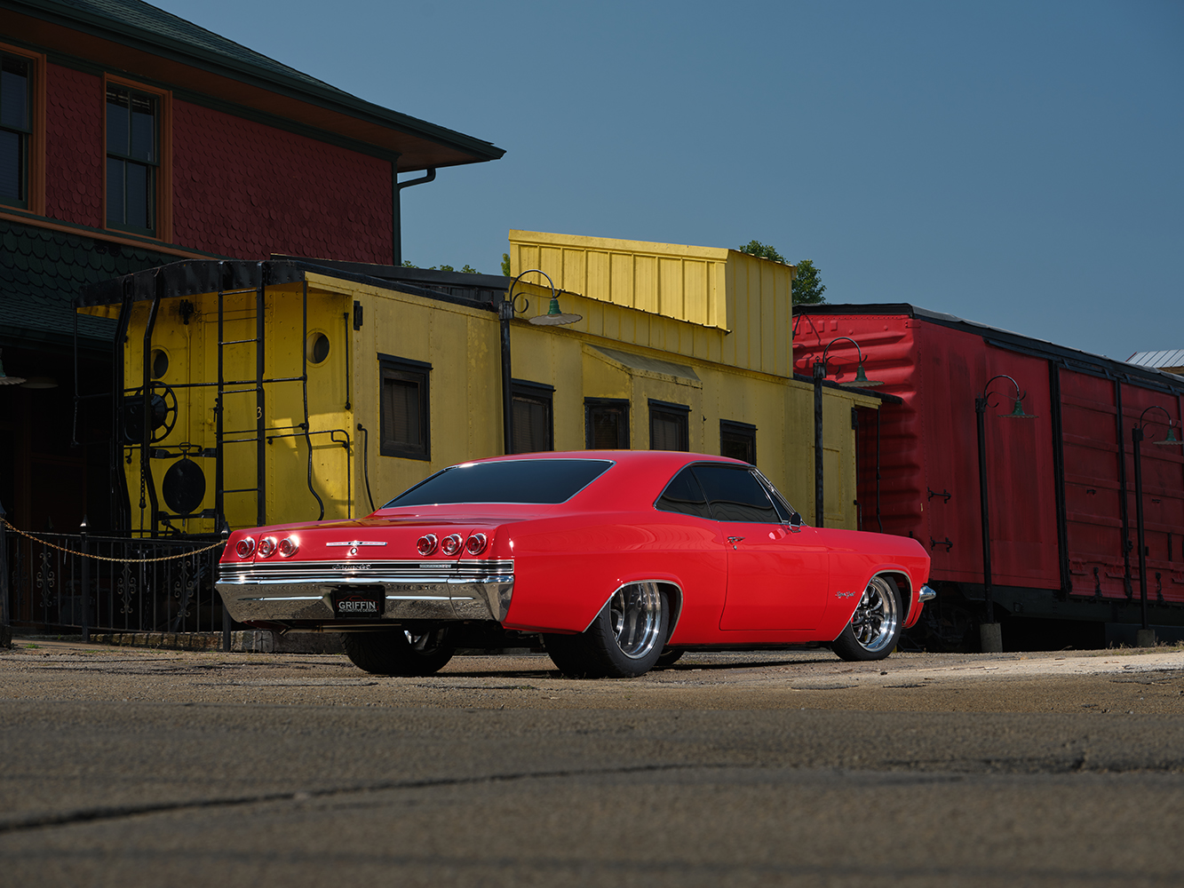 004 1965 Chevrolet Impala SS red rear three quarter view showcasing chrome bumpers dual exhaust and classic styling