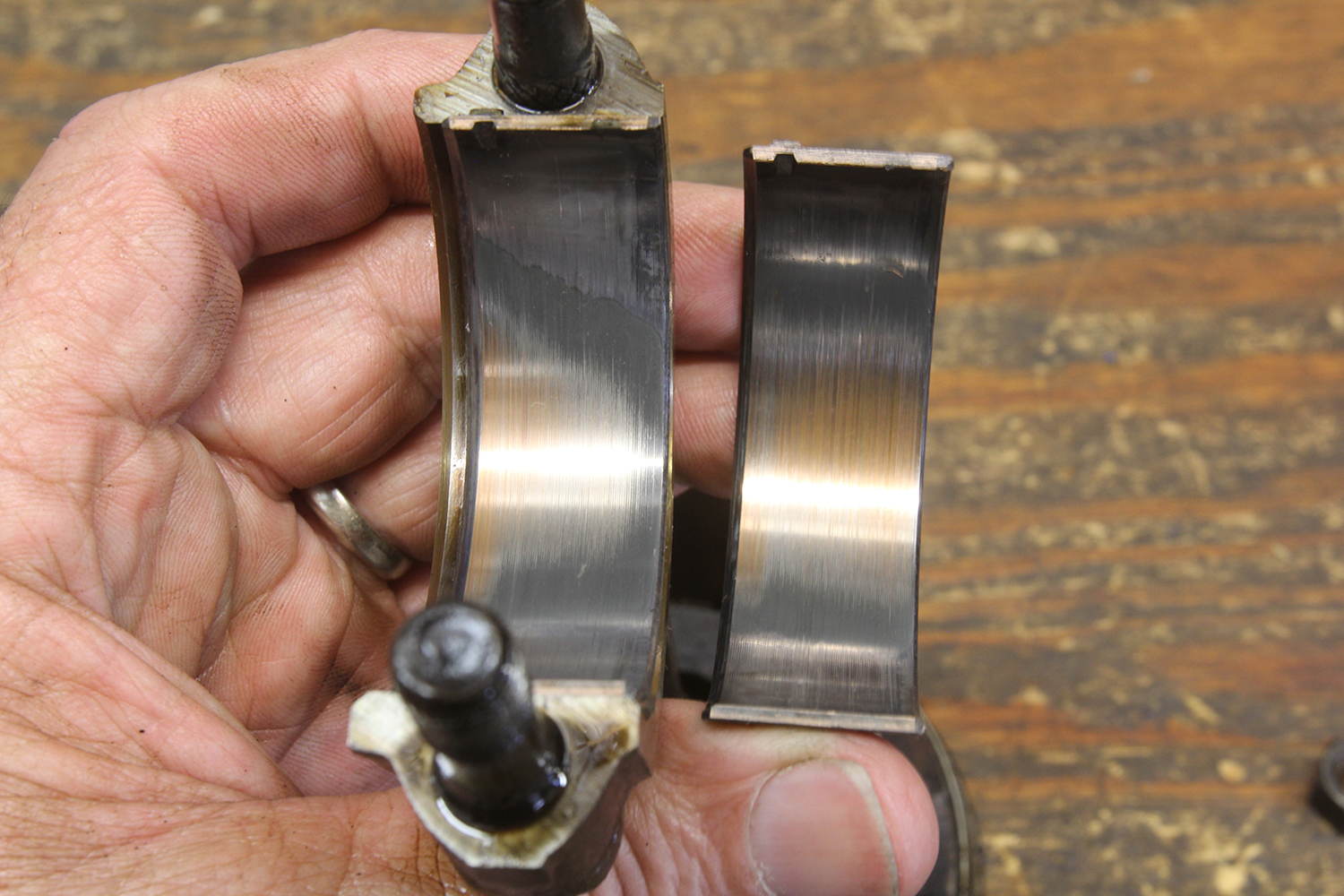 005 Hand holding two engine bearings with visible wear marks and smooth polished surfaces