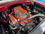 007 1956 Chevy engine bay featuring a tri power Edelbrock setup with custom red orange fins and chrome detailing