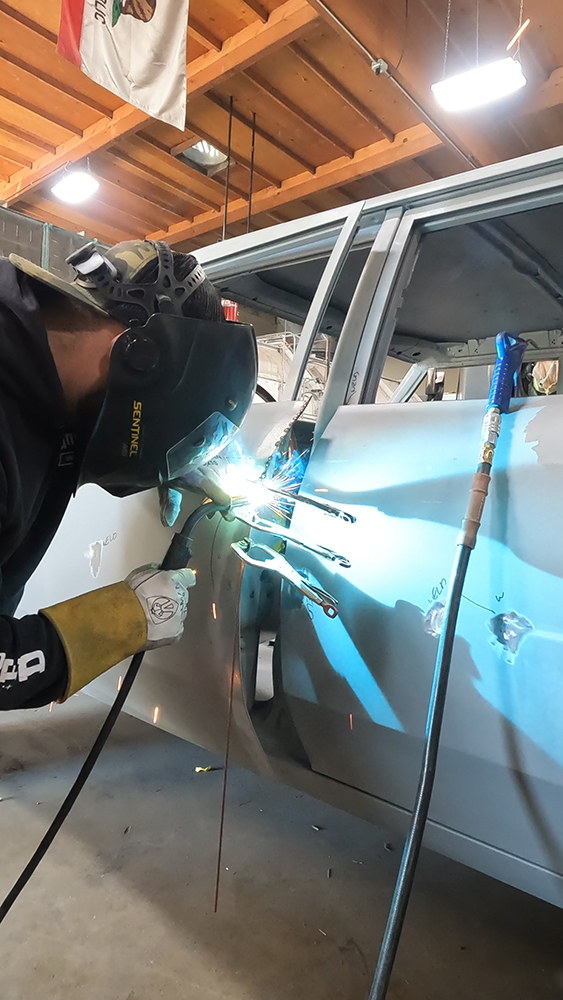 008 Technician carefully finishing weld seams for smooth alignment of door gaps