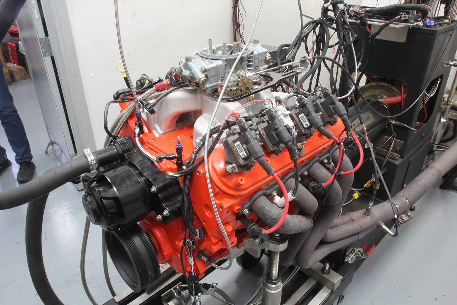 010 High performance V8 engine with orange block and carburetor setup undergoing dynamometer testing with connected wiring