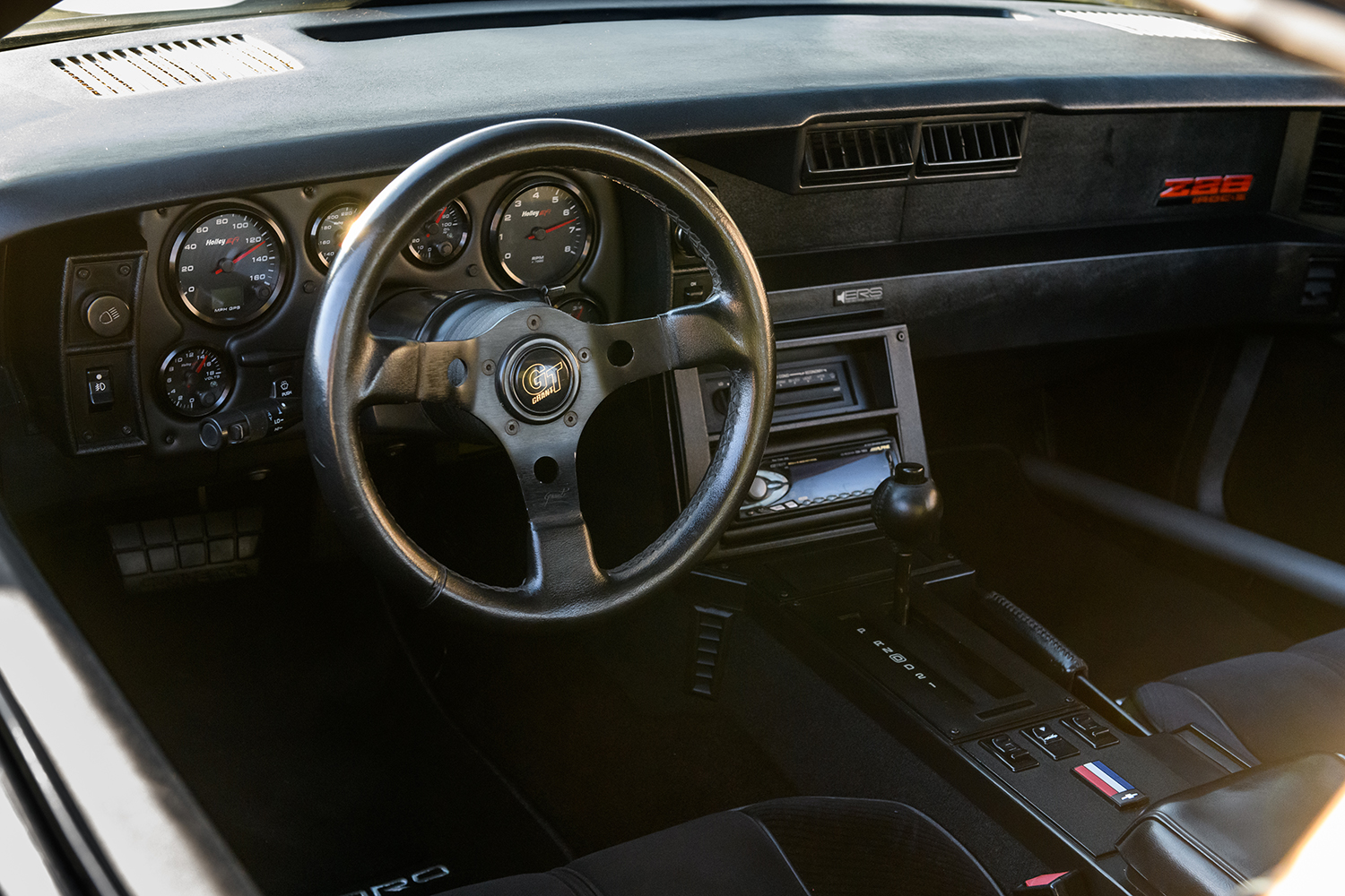 014 1986 Camaro IROC Z cockpit featuring Grant GT steering wheel and Holley EFI digital gauges