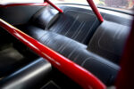 015 1957 Chevrolet Bel Air rear seat in black leather with a red roll cage for a race inspired interior