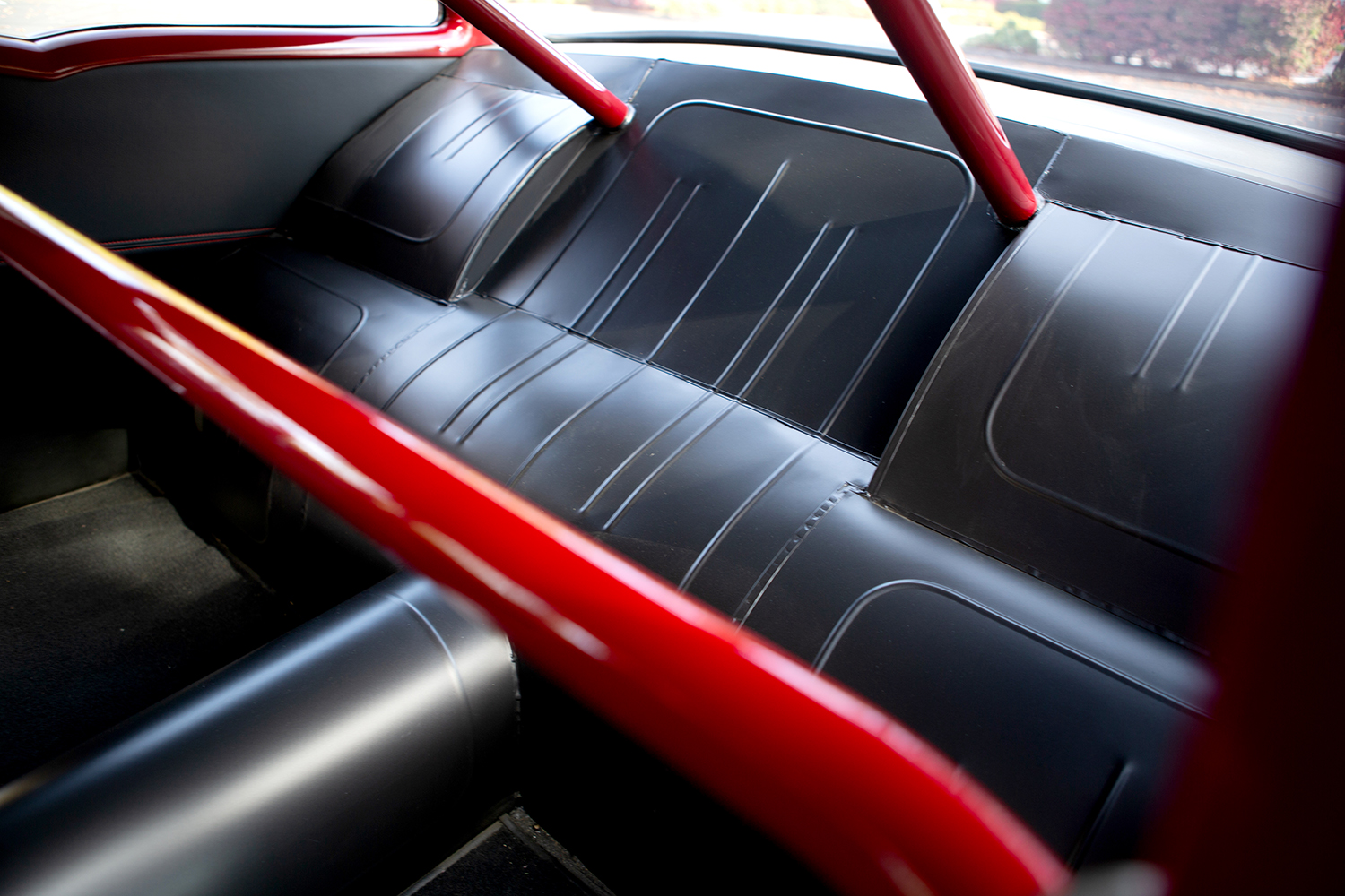 015 1957 Chevrolet Bel Air rear seat in black leather with a red roll cage for a race inspired interior