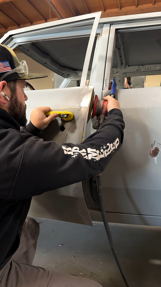 017 Technician refining panel surface for smooth finish in the restoration shop