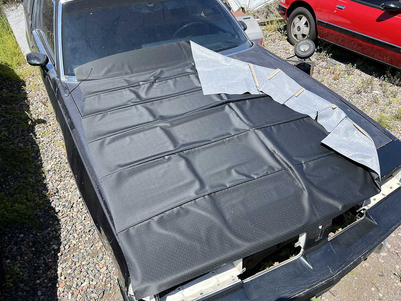 02 New black headliner fabric laid out on the roof of a 1970 Chevy Nova