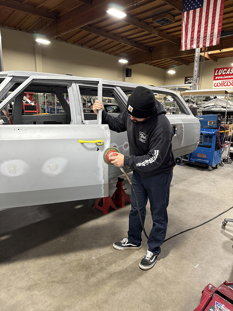 020Technician working with an orbital sander to refine the door panel surface