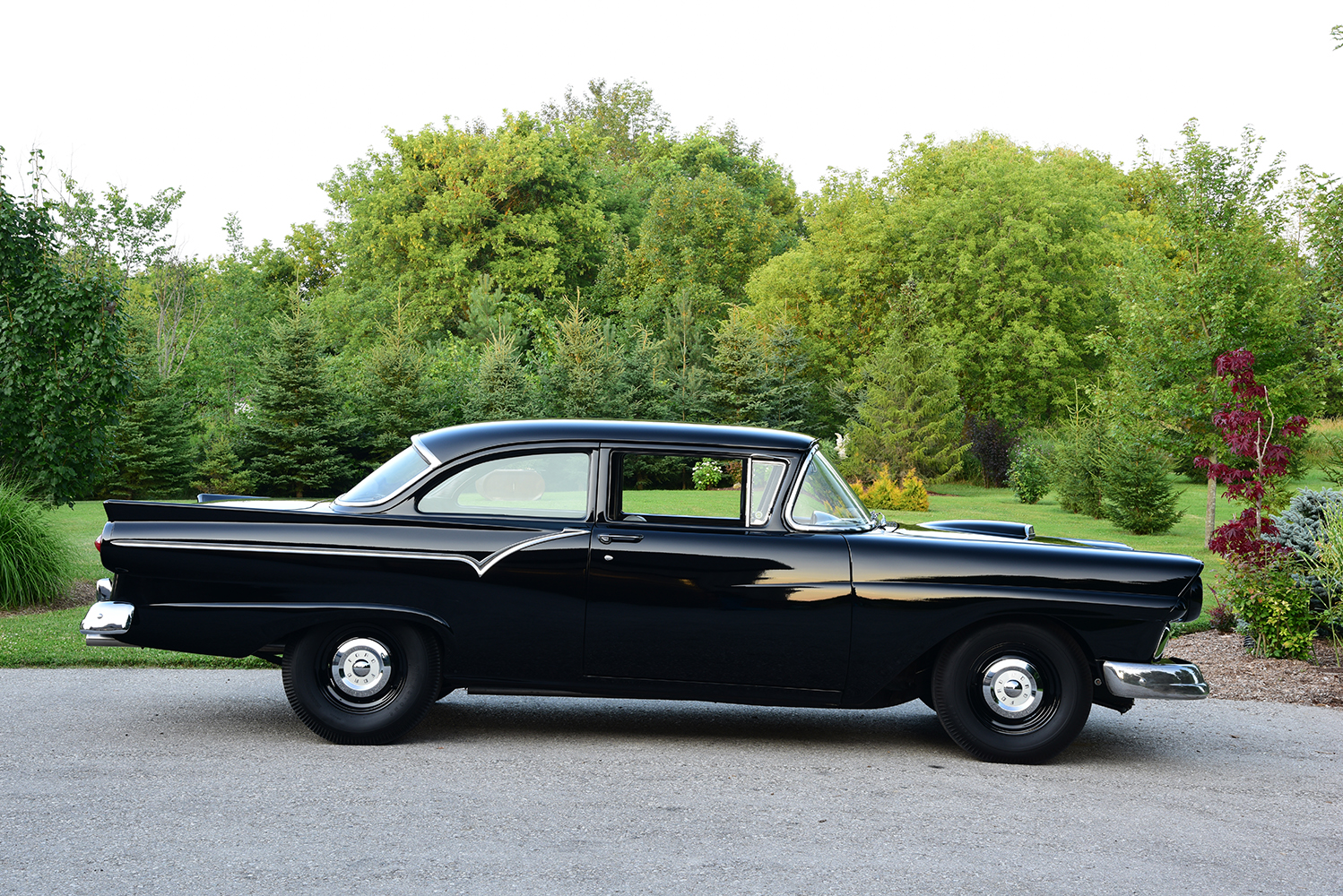 03 1957 Ford Custom Sedan with glossy black paint chrome trim and a sleek stance on steel wheels