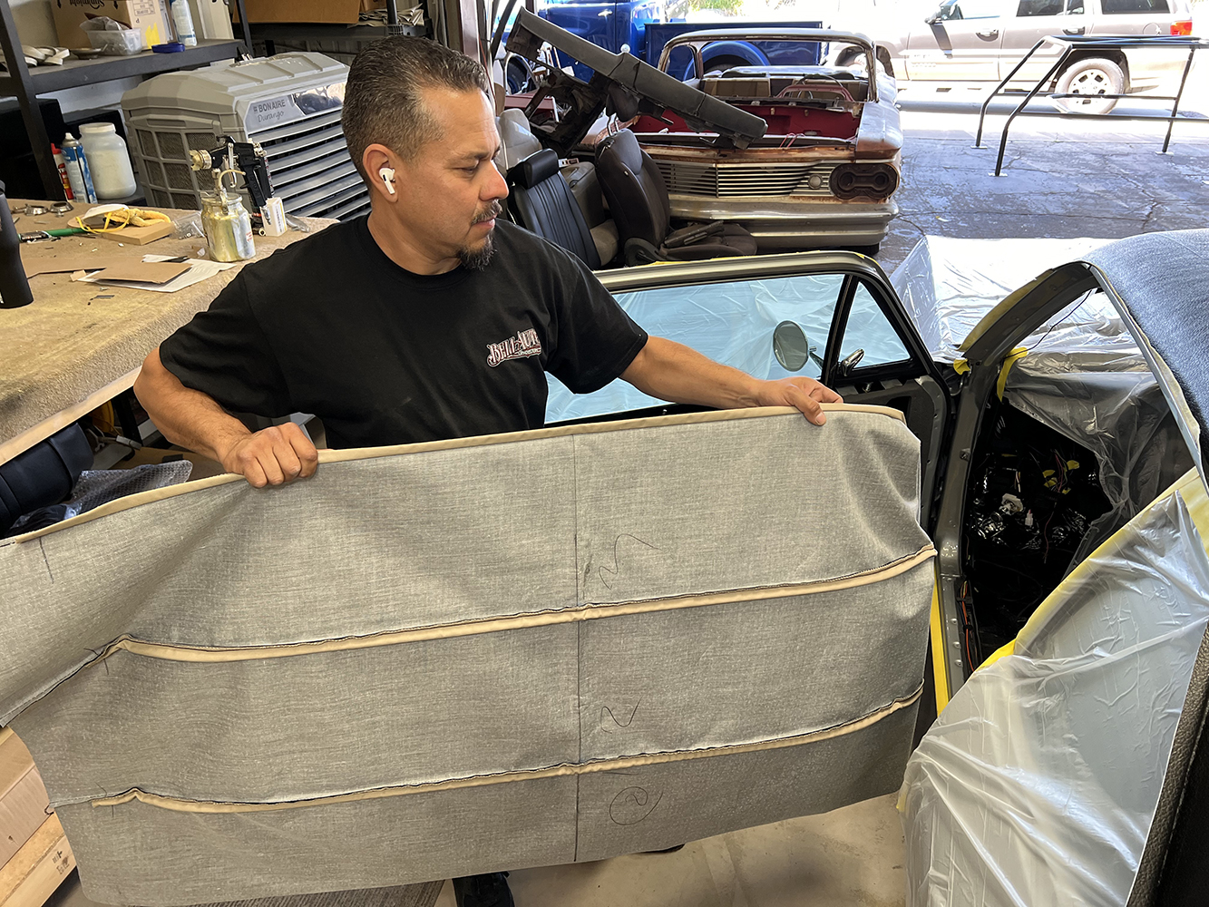 05 Worker holding prepped headliner fabric before installation in a 1970 Chevy Nova