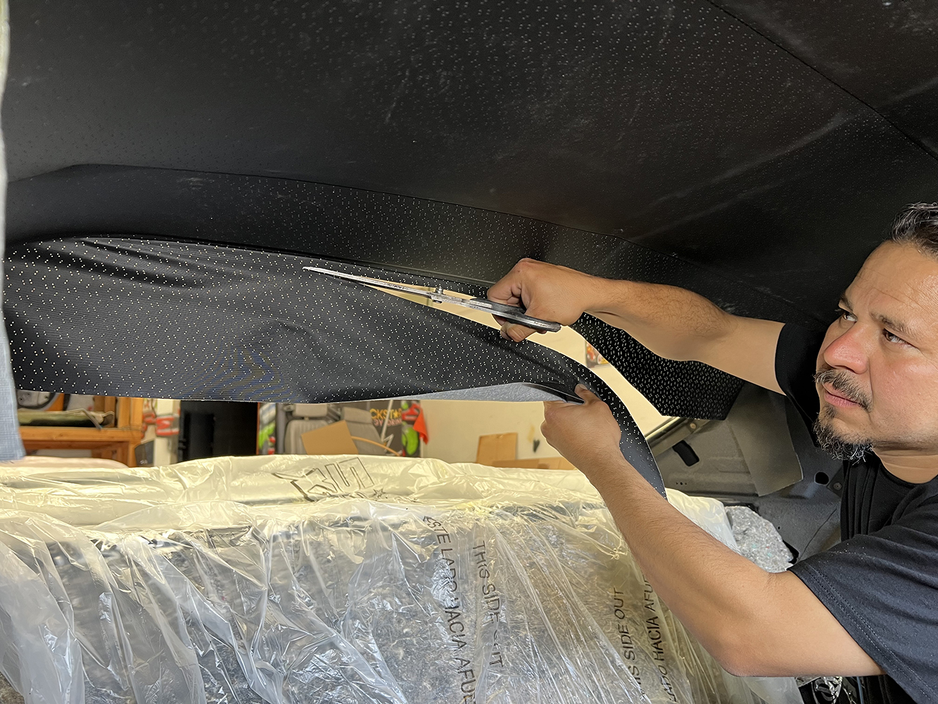 12 Worker trimming excess fabric for a precise headliner fit in a 1970 Chevy Nova