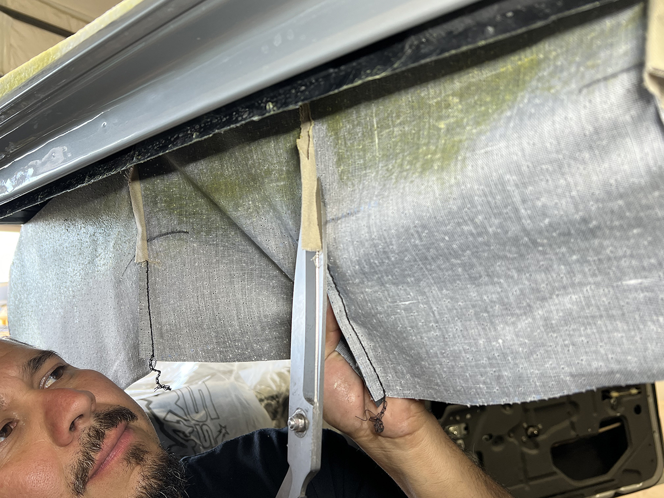 13 Cutting the headliner material near the edges for proper installation in a 1970 Chevy Nova