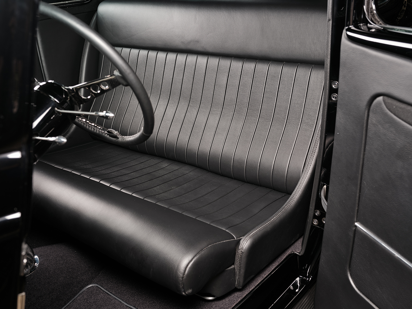 14 1933 Ford Five Window Coupe interior with a sleek black leather bench seat and minimalist styling