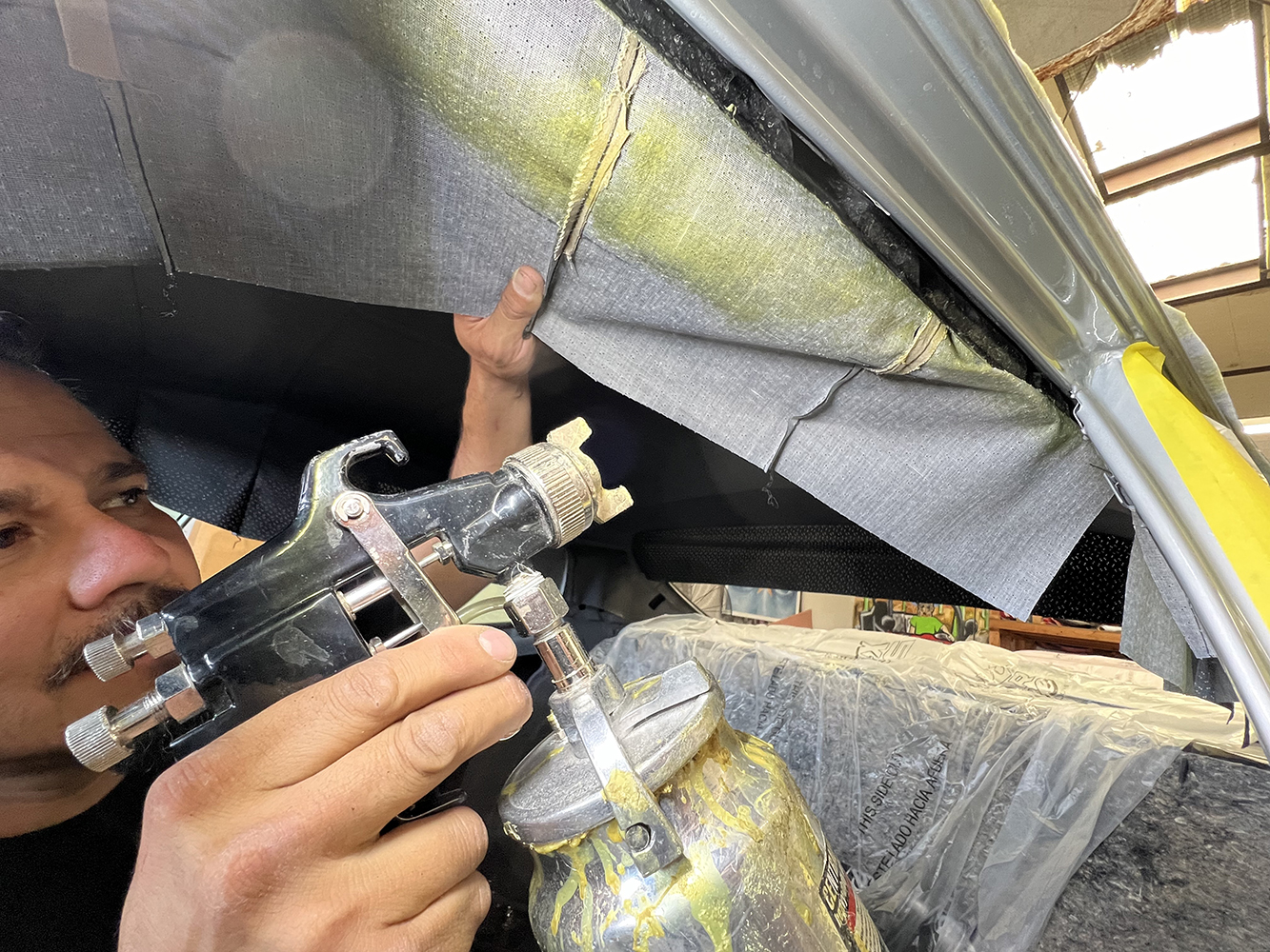 14 Applying adhesive to secure the headliner fabric inside a 1970 Chevy Nova