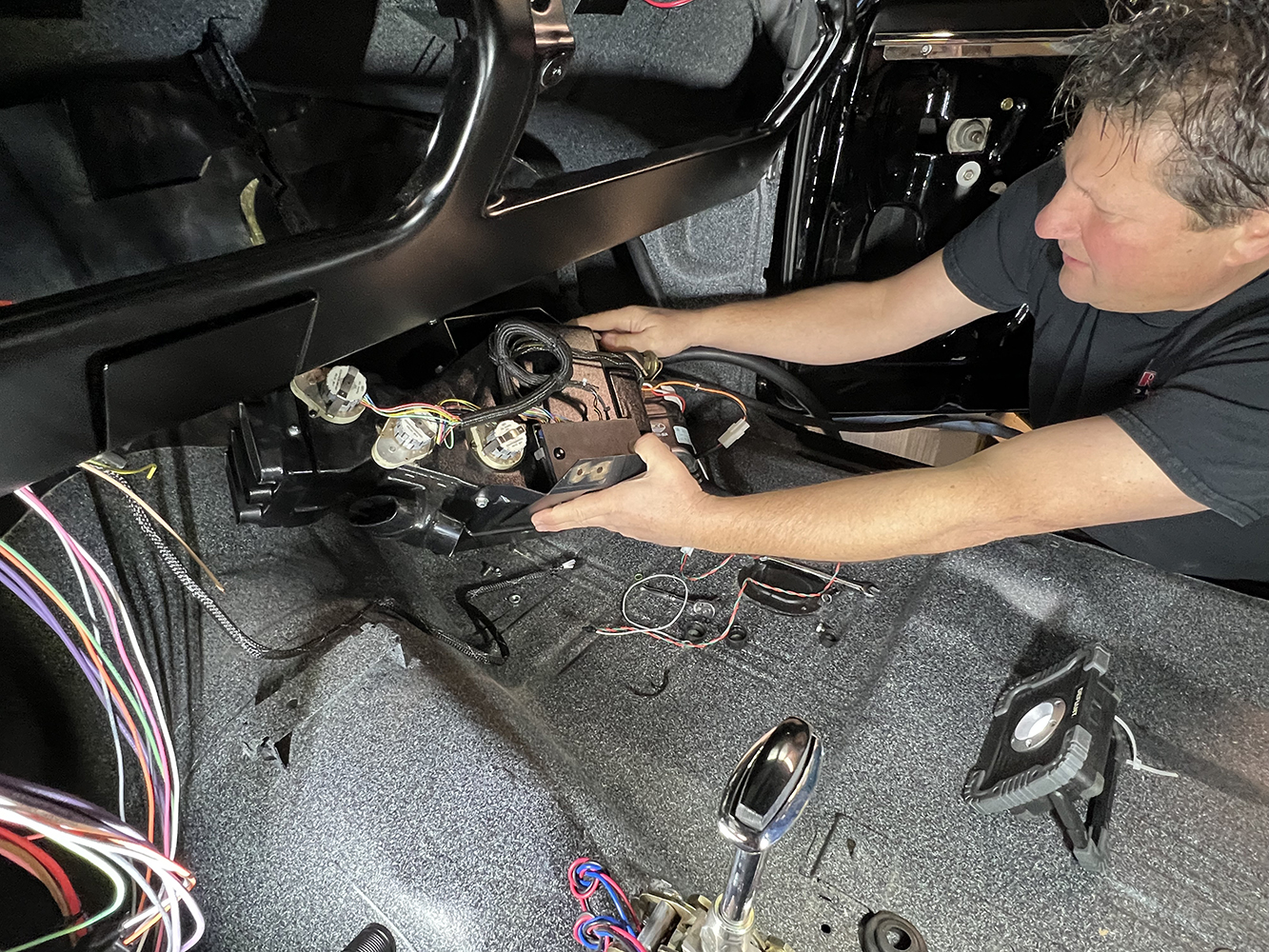 16 Technician installing a Vintage Air evaporator unit inside a classic car dashboard with exposed wiring
