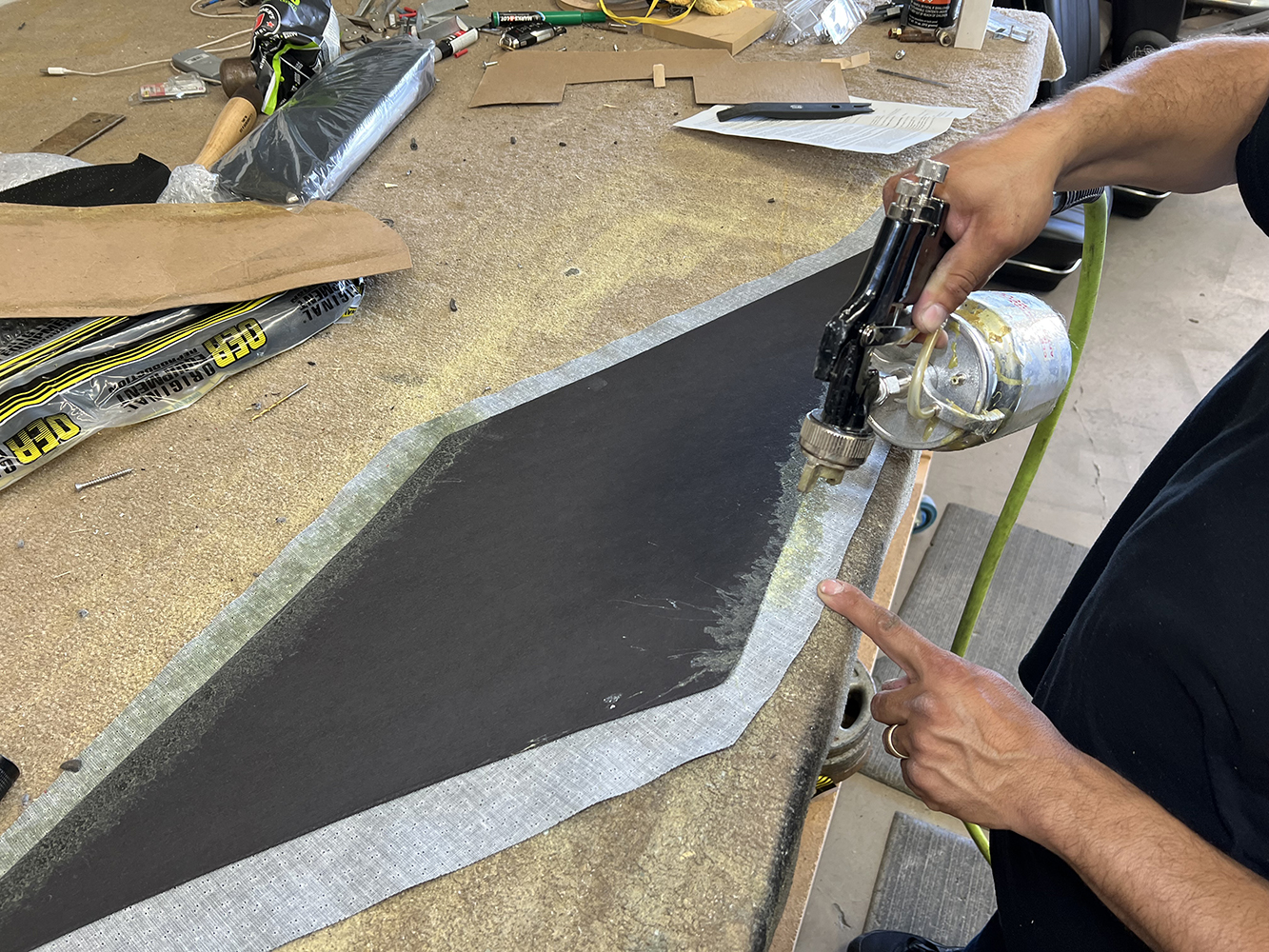20 Spraying adhesive onto a trim panel for final upholstery touches in a 1970 Chevy Nova