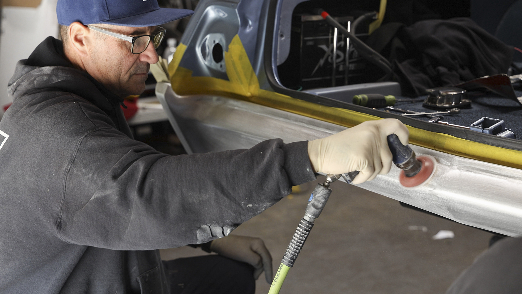 21 A craftsman polishing the lower rear quarter panel on a 1962 Chevy Impala for a smooth finish